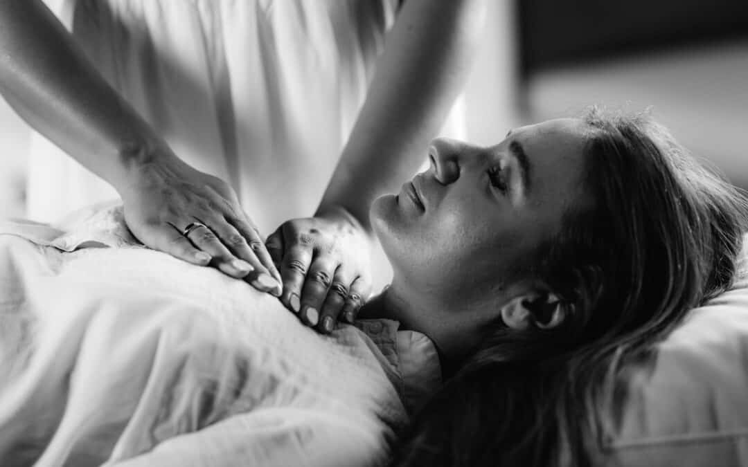 Black & White close up photo of a Reiki therapist hands, placed on a female client's upper chest, as part of a tailored Energy Healing treatment at The Healing Practice in Sydney.