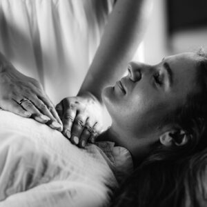 Black & White close up photo of a Reiki therapist hands, placed on a female client's upper chest, as part of a tailored Energy Healing treatment at The Healing Practice in Sydney.